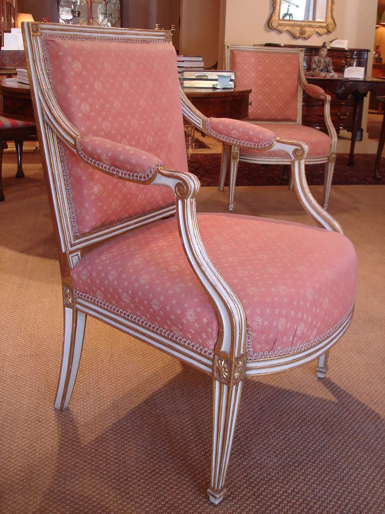 A pair of George III white painted and gilt armchairs of neoclassical design. The reeded back and legs gilt heightened and accented with carved paterae. Upholstered in Mulberry 'Contessa' damask.

Circa 1780