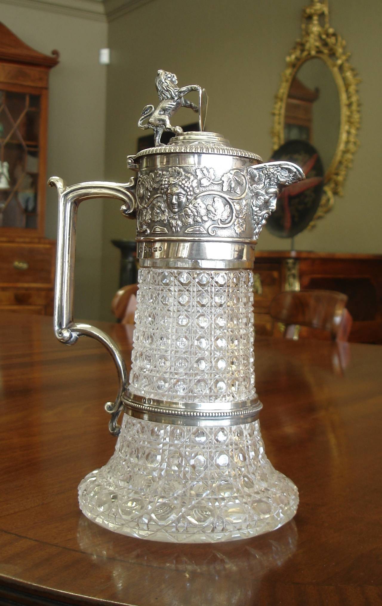 A Victorian period silver mounted and cut-glass claret jug. Hallmarked for Frederick Elkington, Birmingham, 1886, the hinged lid with lion and shield finial, the collar with bacchanalian mask and grape vine decoration, all containing a hobnail cut