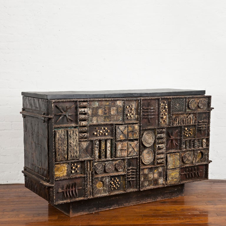 A unique two-door Sculpture Front cabinet by Paul Evans, with hand-cleft slate top and yellow lacquer interior with two adjustable shelves. With welded date and signature to the lower right door [Paul Evans '69]