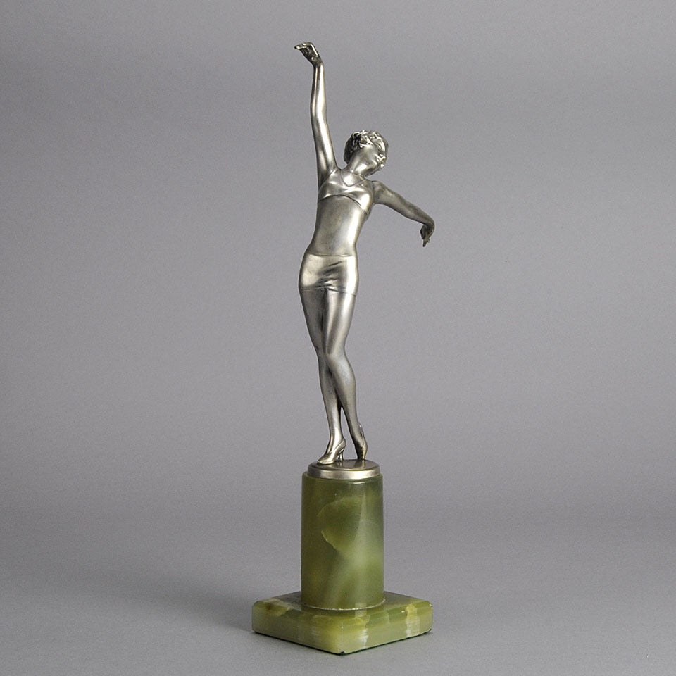 A dramatic cold painted silver bronze figure of a stretched dancer in elegant bikini style dance costume and high heeled shoes. The bronze with good color and detail on integral bronze base signed Lorenzl, raised on a shaped green onyx