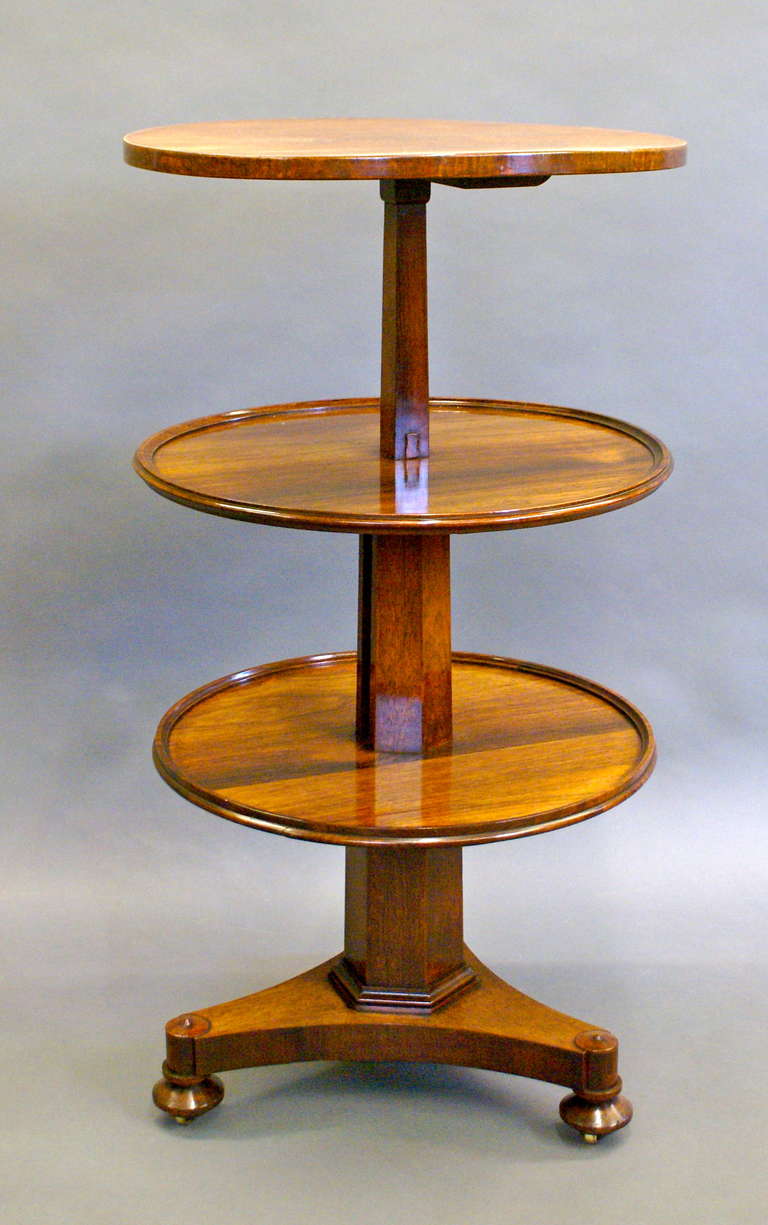 By pushing a button at the base of the second tier and pushing down on the top tier the bottom tier (by means of a pulley system) rises and forms a tripod. This unusual piece is in very good original condition and is of good colour and patina.