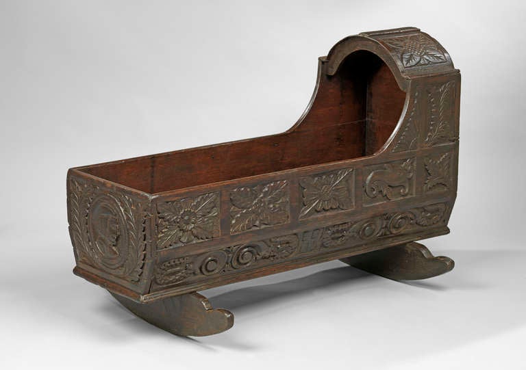 A good example of an oak rocking cradle, the whole decorated with carved panels including a male portrait at the end, fish, flowers and initials, in the 17th century Baroque taste. 

North European.