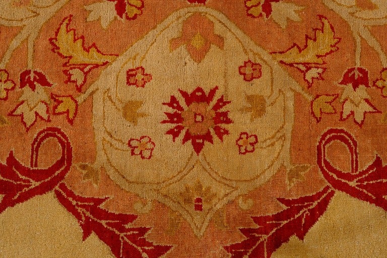 Agra are among the finest Indian carpets, At the center of the field a grand red medallion with arabesque detail sprouts complex finials, balanced by ivory cornerpieces with similarly elaborate internal detail. Vinescrolls writhe gracefully across