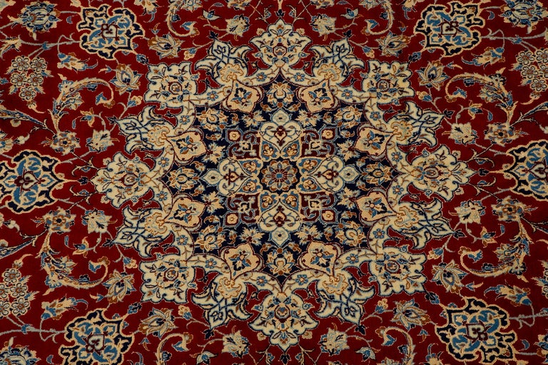 This spectacular Nain rug features a prominent  medallion flanked by flamboyant pendants with recurved tendrils and lush vinescrolls. Magnificent floral motifs and spiraling vinescrolls decorate the midnight blue spandrels and creamy ivory field. 