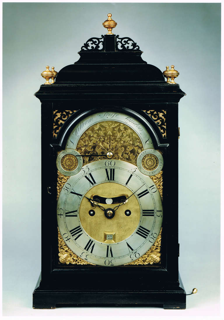 A good quality antique, ebonized brass dial bracket clock by this 18th century 'maker of repute'. The moulded and veneered case has an inverted bell top, which is surmounted by five brass finials and a delicately carved fret. The front door has