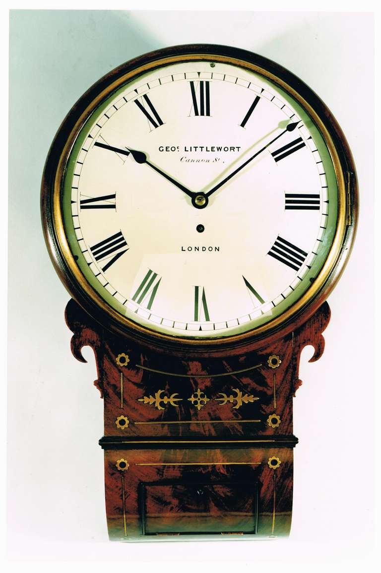 A good early 19th century drop dial wall clock with finely patinated and figured mahogany trunk with original brass inlays. The 12 inch convex dial has a white painted convex dial and fine tapering blued steel hands. 
The moulded mahogany bezel is