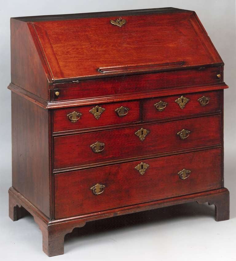 A good quality George II period antique bureau in well figured walnut, standing on bracket feet and with replaced handles and escutcheons. It has a fall front with a loper support at each end and is set above four long finely graduated drawers. The