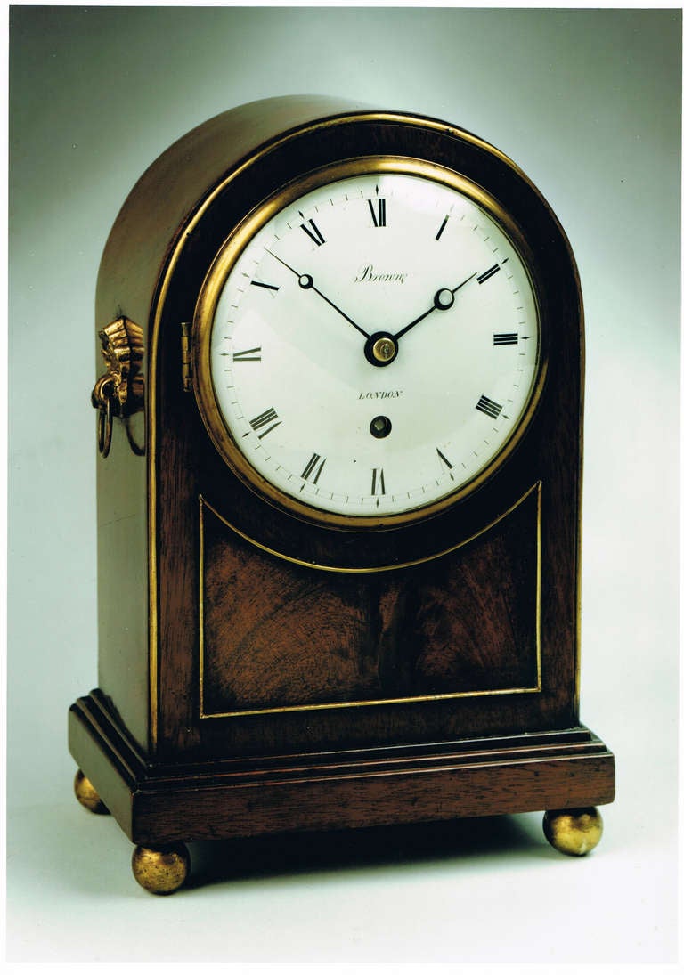 A good small late Georgian mahogany mantel timepiece, the arched mahogany case with gilt brass bead outline edging to the front, ring side handles and raised on ball feet. 

The 4.5 inch enamel dial signed Brown, London, with blued steel moon