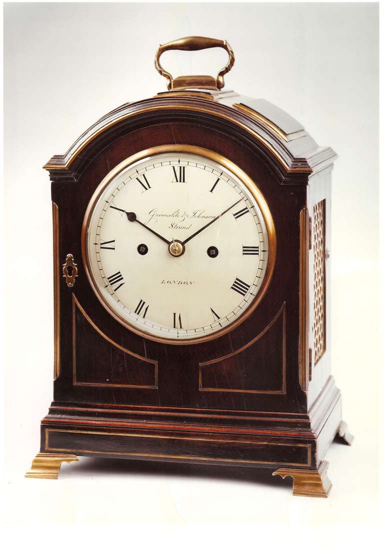 An antique late George III period ebonized bracket clock by Grimalde and Johnson, strand. This attractive clock of small proportions, has a moulded arch top with three brass edged rectangular panels and a brass carrying handle.

The sides have