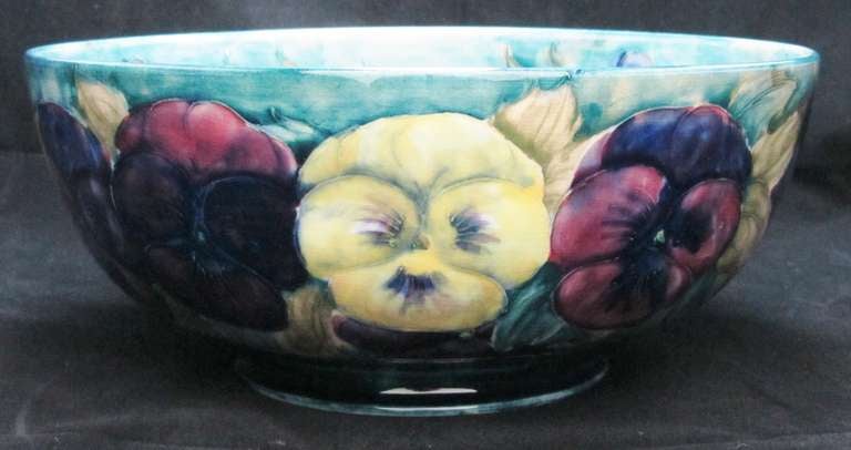 William Moorcroft Bowl decorated in the early version of the pansy and bud design on a green/blue background. Minor scratches to interior.