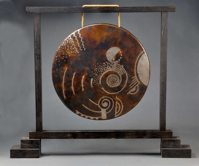 Rare gong in cloudy brown, hammered copper ware inlaid with geometric and concentric silver motifs. Held on a solid ebony support (later date). Model created circa 1925.

H : 30 1/2 in L : 37 in D : 3 1/2 in

Diameter : 20 in

Bibliography :