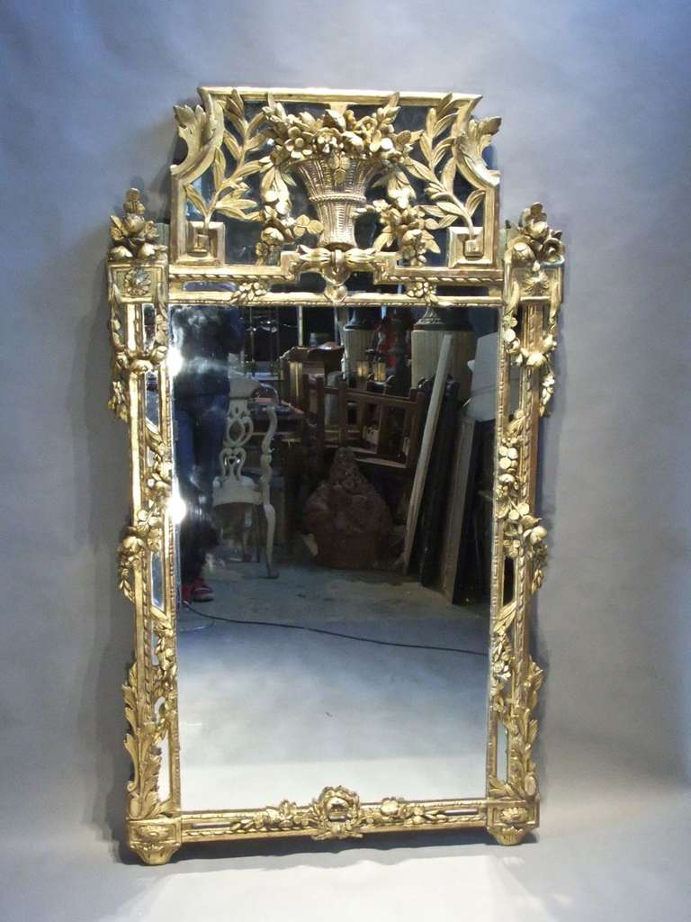 An exceptional Louis XVI carved and giltwood mirror with intricate floral swags.
