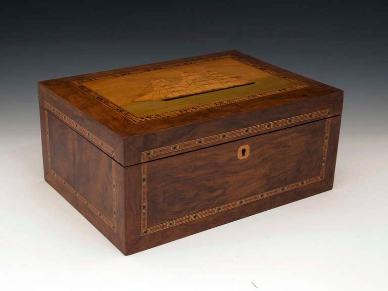 Walnut Work Box with a view of a Tea Clipper / Sailing Ship which is flying two flags one of which is the british flag. The ship is frame with checquered and herring bone inlay of stained sycamores and boxwood, similar inlays surround each walnut
