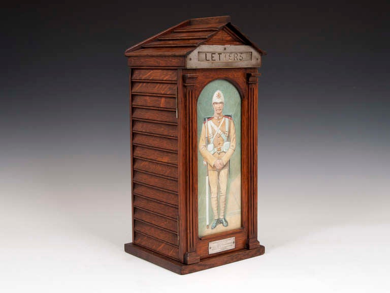 Country house oak letter box in the form of a sentry box. 

Has a glazed door with a watercolor of a soldier from the Boer War, by famous military artist Richard Simkin. 

The inside of the door features the famous army and navy store plaque.