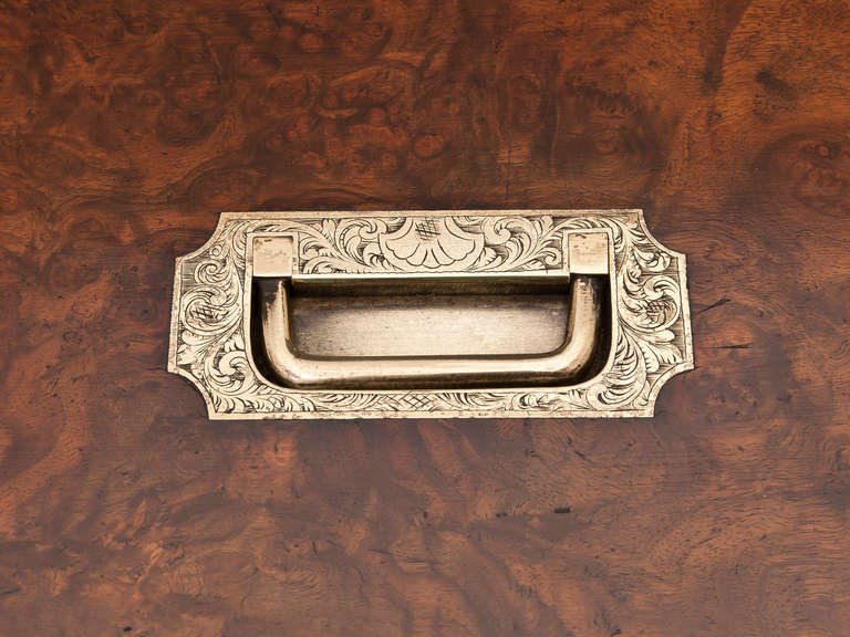 Burr Walnut Jewelry box brass bound with engraved carrying handle on the lid and escutcheon on the front.

Opening the box reveals further elaborate engraving on the brass around the closing edge of the box. The lid houses a removable mirror with