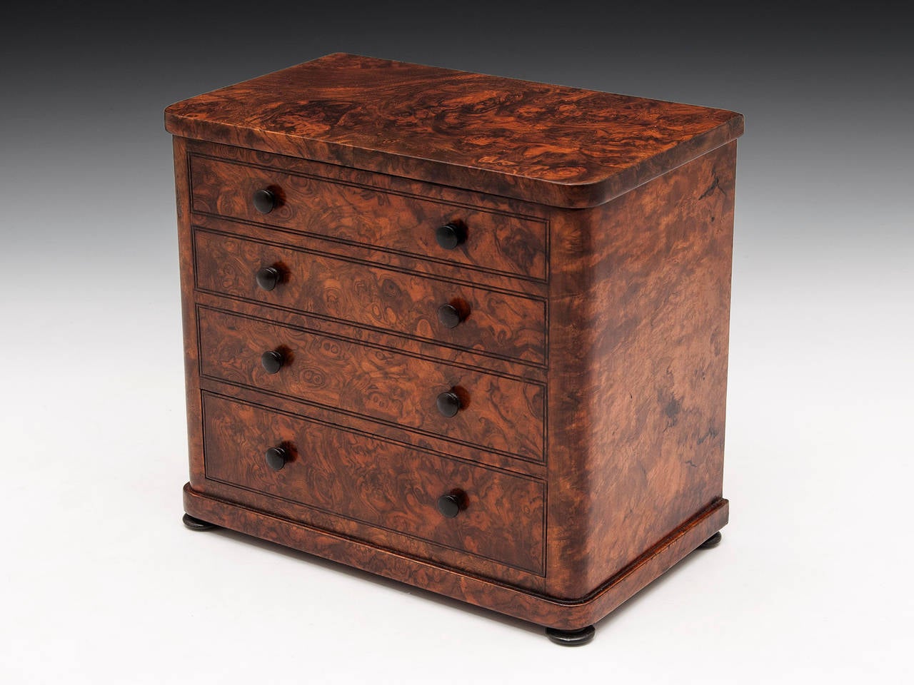 Charming Smokers’ Companion modelled as a Miniature Chest of Drawers, veneered in stunning burr walnut. It has eight turned ebony handles; one of these, when pressed, opens the sprung hinged top to reveal three compartments for cigars and tobacco.