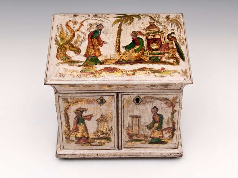 An exquisite little Regency cream gilt Japanned sewing table cabinet. Decorated on the top and front with gilt chinoiserie and brightly colored figures set in exotic landscapes. The sides, back and interior show further exotic scenes on a cream back