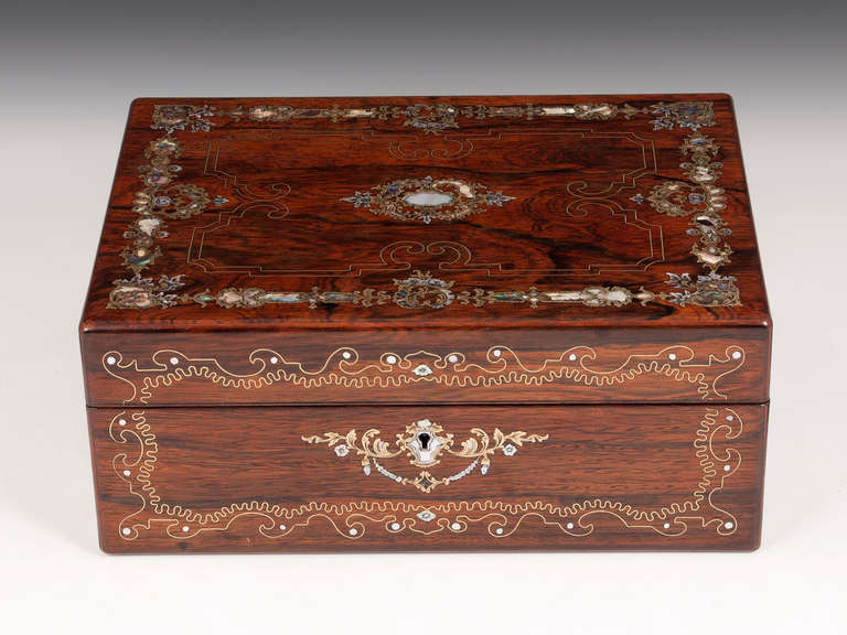 Jewellery box veneered in beautifully figured Rosewood with exquisite inlaid mother of pearl and detailed fine brass stringing.

The interior features a lift out tray with several velvet and leather paper compartments included two padded