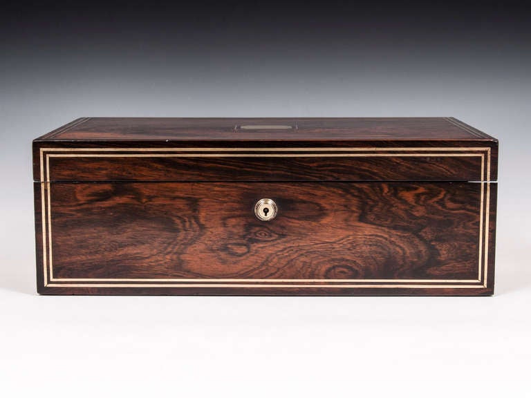 Edwards Writing box veneered in wonderfully figured rosewood with double brass stringing framing the front and top. The sides feature flush fitted brass campaign handles.

Inside features its original gold tooled purple leather writing surface, a