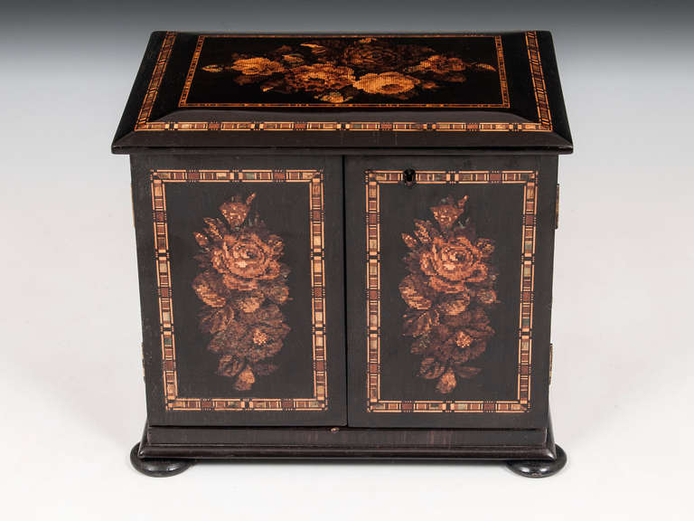 The cabinet is adorned with bordered floral designs on the front and top. The doors open to reveal three drawers which are decorated by the same border pattern with inlaid ebony tunbridge handles. 

The Tunbridge label to the base reads: 
T.Barton,