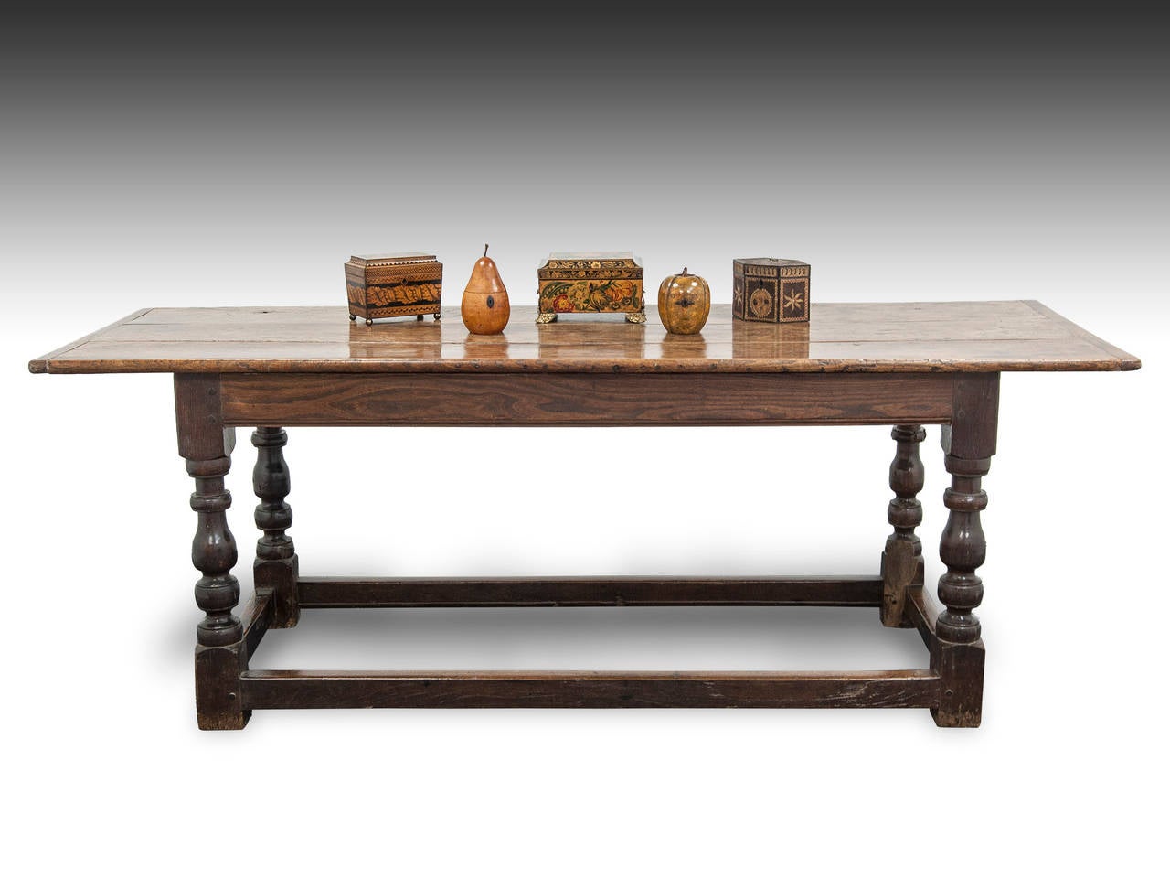 Sublime unmolested refectory table featuring a cleated three plank to made from elm with a generous overhang on each end.

The oak base features baluster legs and elm side rails.

This table is in original order with no replacements.

The tea