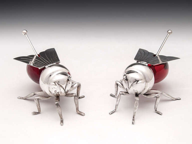 Matched pair of Silver plated Bee Jam pots with cranberry coloured glass by famous silversmiths Mappin & Webb of London & Sheffield, both containing spoons with one having an engraved pattern. The wings have are hinged and lift to enable you to