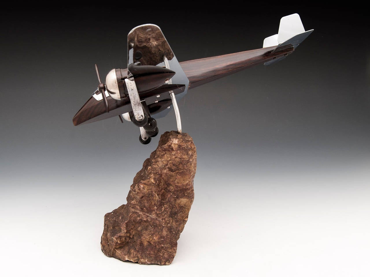 Art Deco model of an aeroplane made with solid Macassar ebony and silver plated brass. The propellers and landing gear both turn. 

Standing on a stone plinth which the plane can swivel on. 

The smaller plane pictured is not included in this