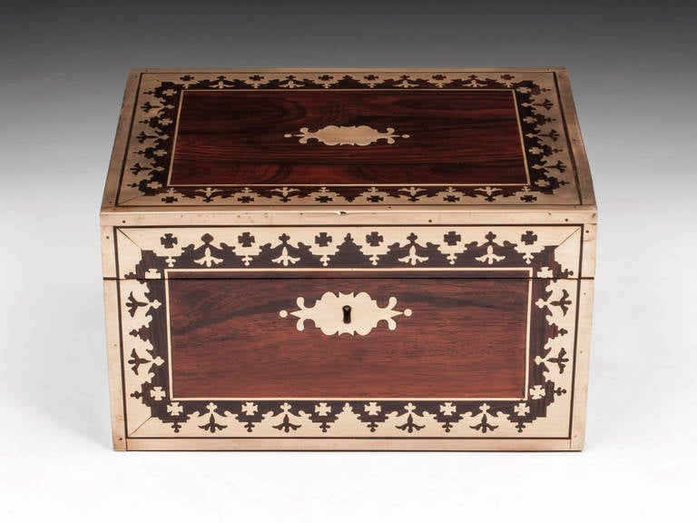 Brass bound rosewood jewellery box with decorative inlaid brass borders on the front and top, brass escutcheons and flush fitting carry handles.

The interior is lined in striking blue velvet and leather paper and features a removable tray with