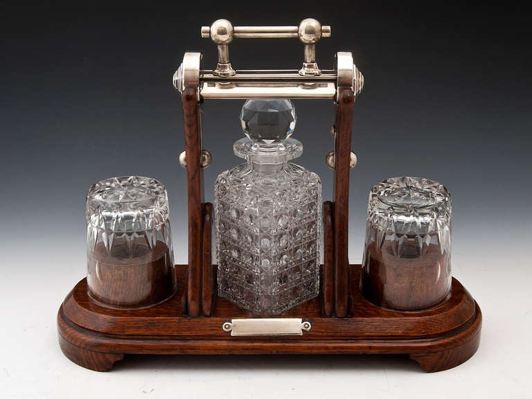 Oak Tantalus with single crystal cut glass hobnail decanter with faceted stopper & star cut base and two gut glass glasses, all housed in this superb oak & silver plated frame which has a patented locking mechanism by GRINSELLS of Birmingham who