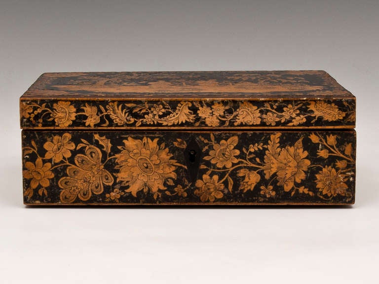 Penwork Sewing Box with three chinoiserie figures in a garden on the top, with a floral border. The floral pattern continues around the rest of the box. 

The interior has several compartments lined in pink paper. 

This sewing box come with a
