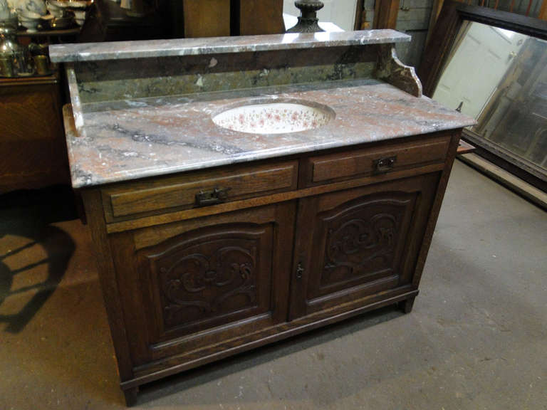 Antique wooden vanity with walnut details and marble top with ceramic decorative painted functional sink.
