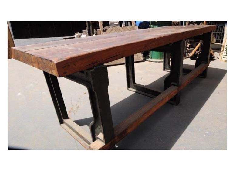 Industrial wooden table with cast iron bases bolted to the hardwood slabs. Beautiful worn out traces of past usage.