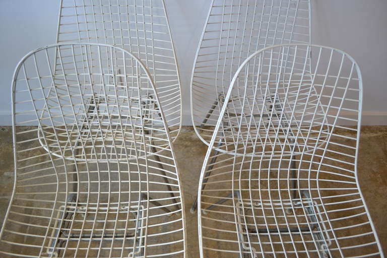 ensemble de quatre chaises eames blanches en fil de fer:: toutes d'origine.