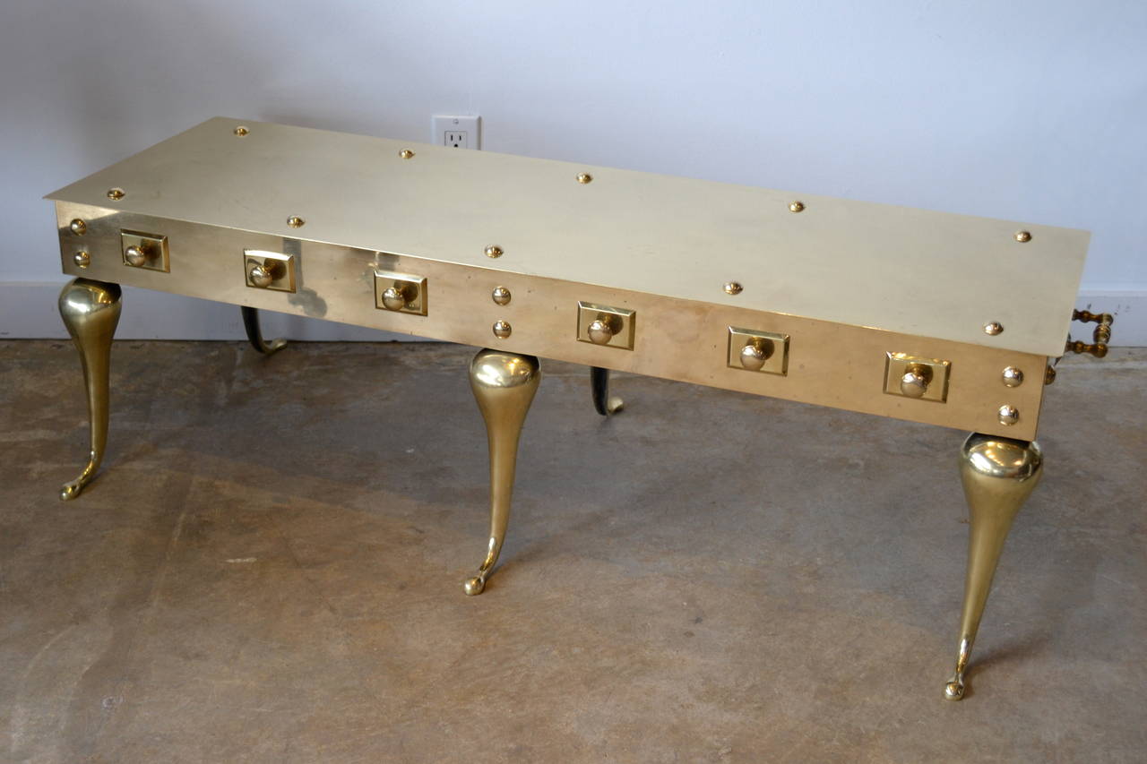 Highly polished brass English footman coffee table embellished with brass knobs, plates and handles. Stunning, 1960's.