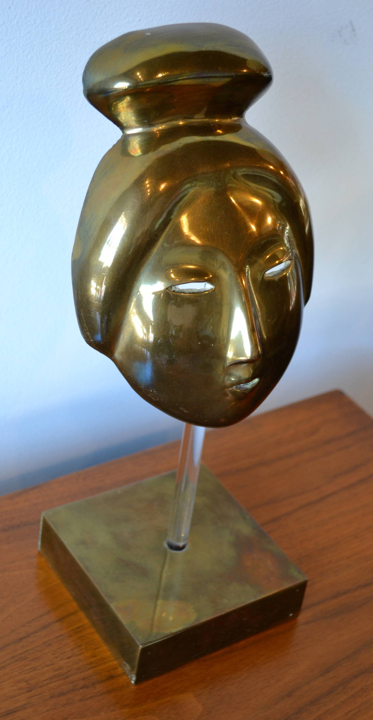 brass face sculpture mounted on lucite and brass base