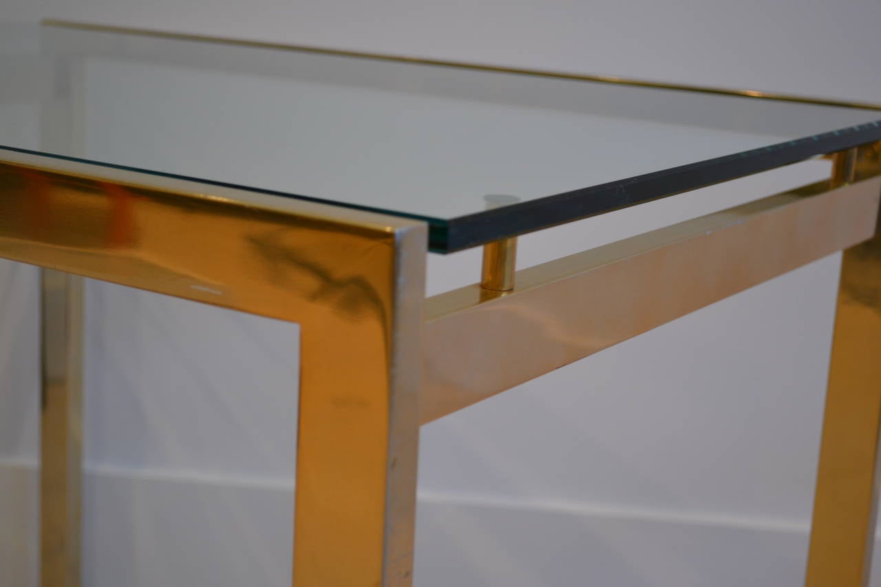 Very sleek and modern side table in lacquered brass with floating glass top.