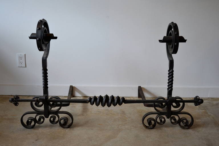 Gorgeous pair of massive hand-forged blackened,  wrought iron andiron set with floating center bar to adjust width. Fantastic details. 1930's.  Great patina.