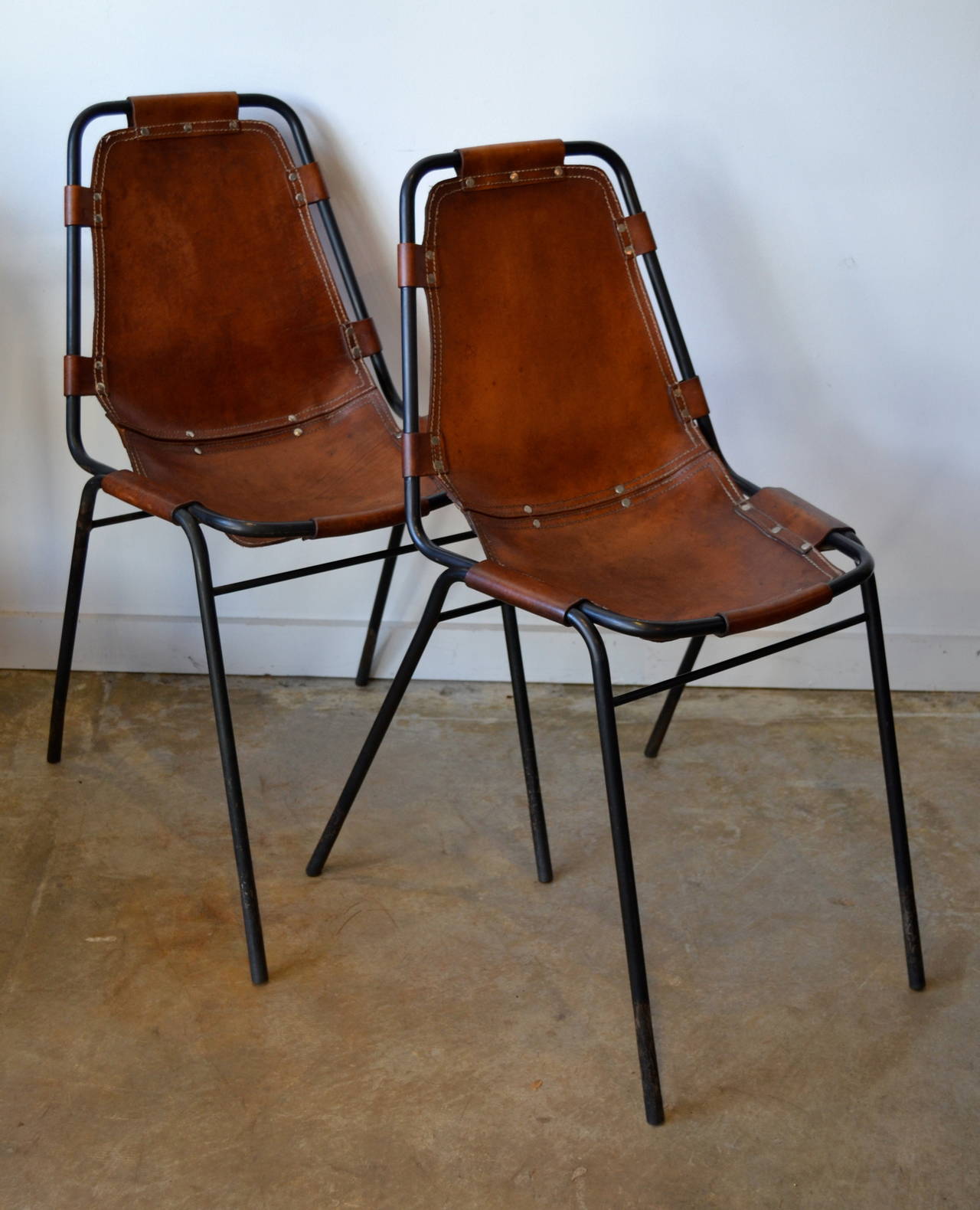 black metal frame and saddle leather side chairs designed by charlotte perriand.