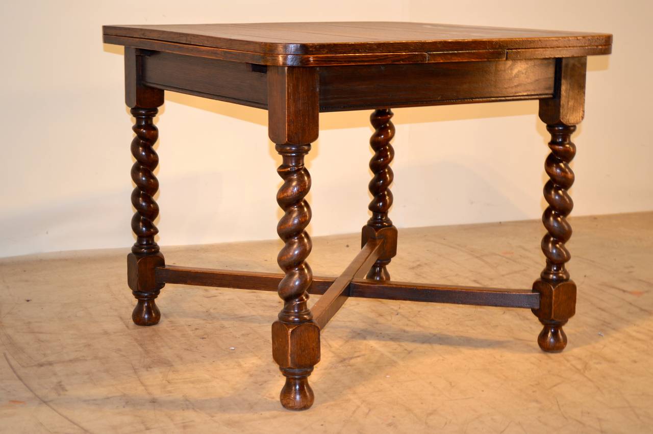 c.1900 English oak table with draw leaves and top that are paneled over a simple routed apron and nicely turned barley twist legs, joined by cross stretchers. Raised on bun feet. The top open measures 59