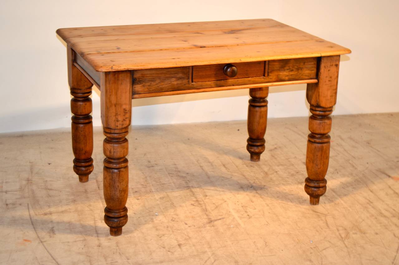 19th century English pine side table with a plank top following down to a simple apron containing a single drawer over turned legs.
