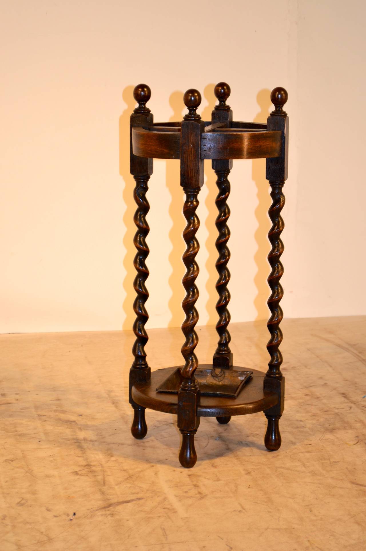 Late 19th century English oak round umbrella stand with original drip tray. Lovely barley twist legs, gorgeous finials and feet.