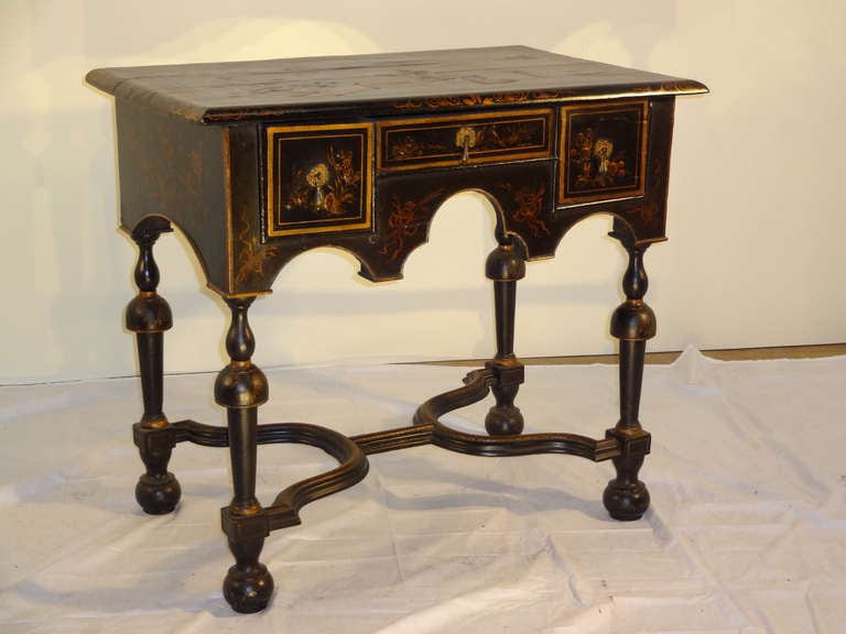 18th century English lowboy hand decorated with chinoiserie decoration.  It is from the Georgian period and has a gloriously hand painted decorated top with a banded edge and a central picture of a garden scene.  The legs are hand turned and are