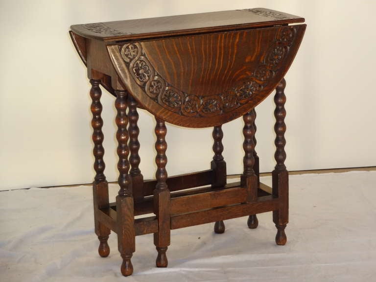 This is a wonderfully grained English Oak gate leg table with great quality carving around the border of the top.  It is in excellent working condition.  The top when open measures 28.25