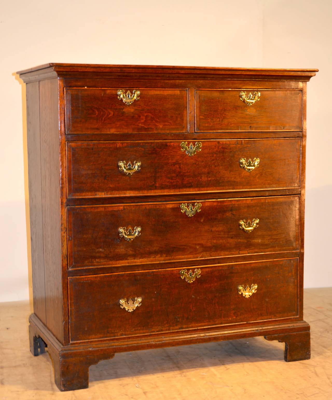18th Century Georgian oak tall chest. It has a two board top, following down to a two over three drawer configuration. The top drawers have small plugs where hardware has been moved or replaced at some time. Raised on nice tall bracket feet.