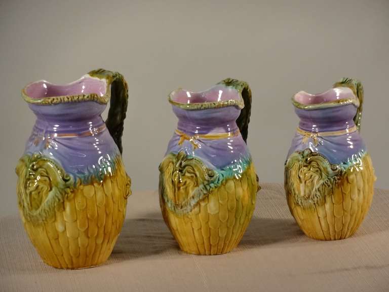 Lovely set of three Majolica pitchers with ram's heads decoration. Small chip inside rim of one pitcher. The medium pitcher measures 6 x 4.75 x 8.25 and the small pitcher measures 5.5 x 4.25 x 7.5.