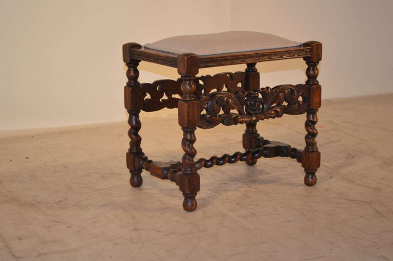 19th-C. French oak stool with turned and barley twist legs, joined by a barley twist stretcher. The front and back of the stool are decorated with gorgeous hand-carved panels.  This piece has been newly upholstered in linen and is decorated with a