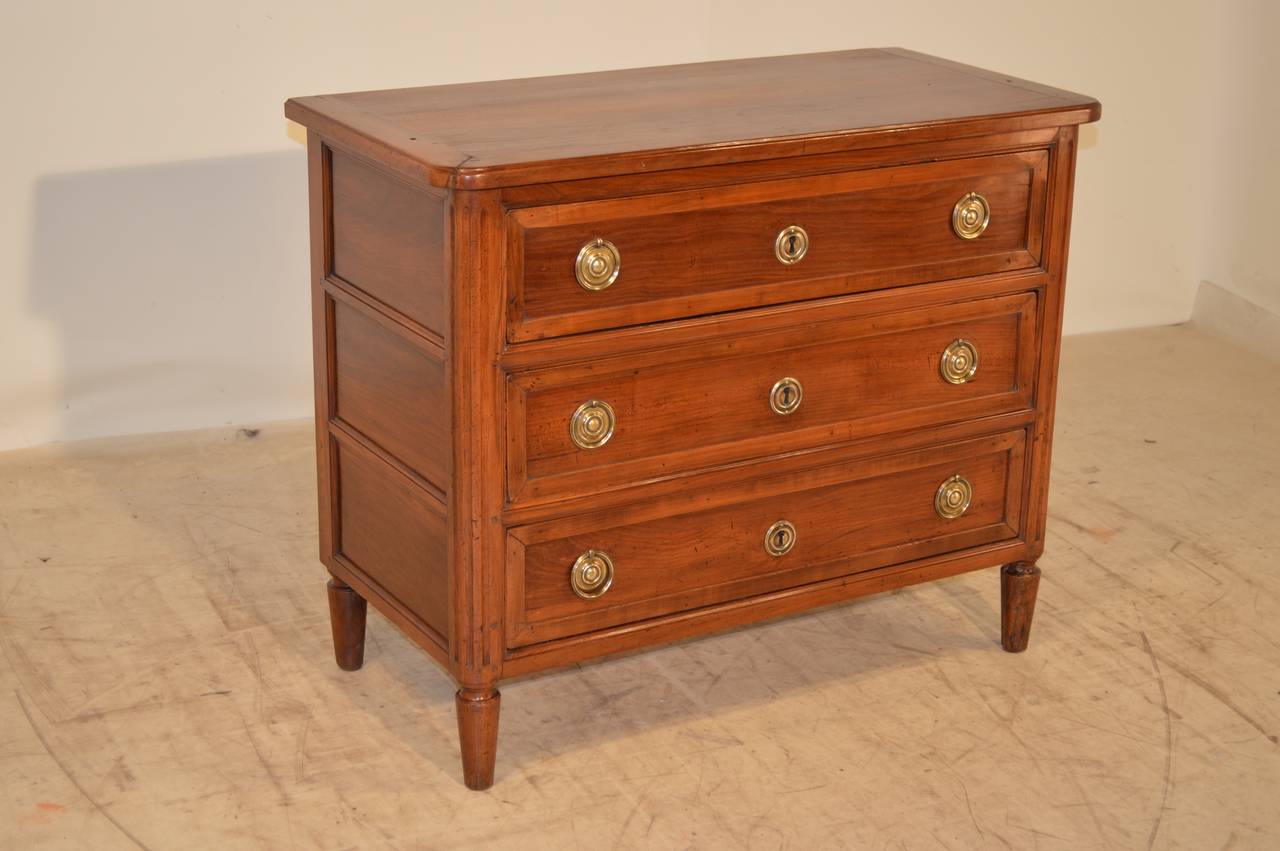 Late 19h-C. French Directoire walnut commode with a single plank top, which is beautifully banded.  The sides are paneled and there are three drawers, which are also paneled with molding.  The corners of the case are fluted and are supported on hand