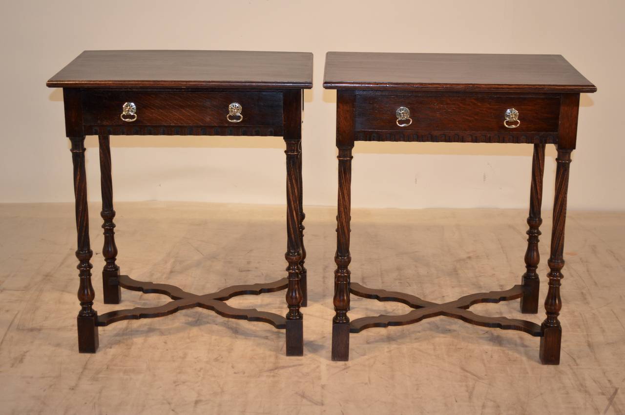 Pair of late 19th-C. English oak side tables with a beveled edge around the top following down to a single drawer with carved decoration underneath.  The legs are hand turned fluted at a spiral direction and finish with turnings.  The legs are