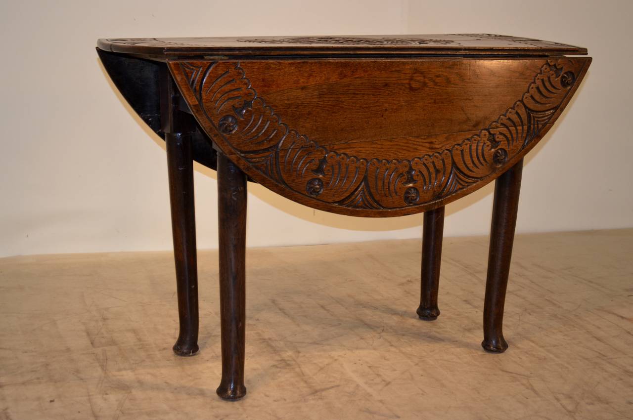 Fantastic and rare English oak gate leg table with wonderfully carved border around the top and a carved central medallion with the date 1653.  The table has a wonderfully simple apron which contains a single drawer and has simple legs and pad feet.