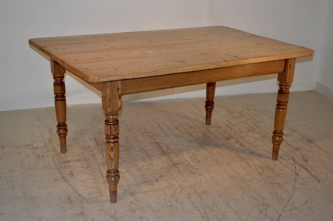 Mid - 19th-C. English kitchen table with a four plank top following down to a simple apron and nicely hand turned legs.  The apron measures 23.88.